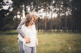 Schwangere Frau wird liebevoll umarmt von ihrem Mann in der Natur - Familienfotograf Brüggen Stephan Sohn
